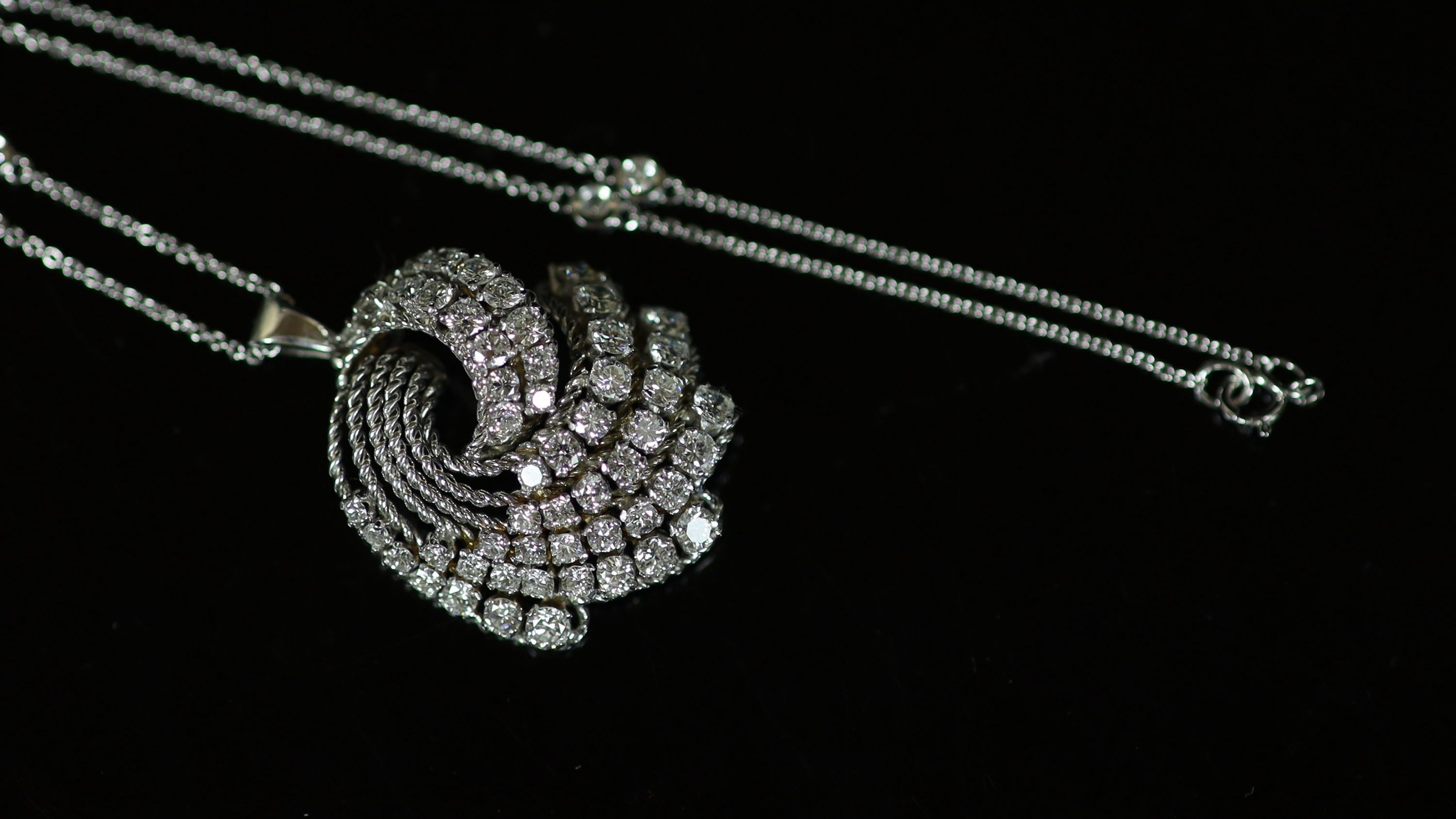 A modern white gold and graduated diamond set fan shaped scroll pendant, on a eight stone diamond set 18ct white gold chain